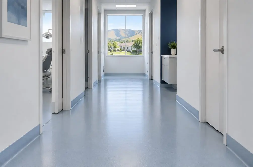 Illustration: a quiet Hayward dental office hallway with a seamless pale blue-gray coated floor and a coved base along the wall