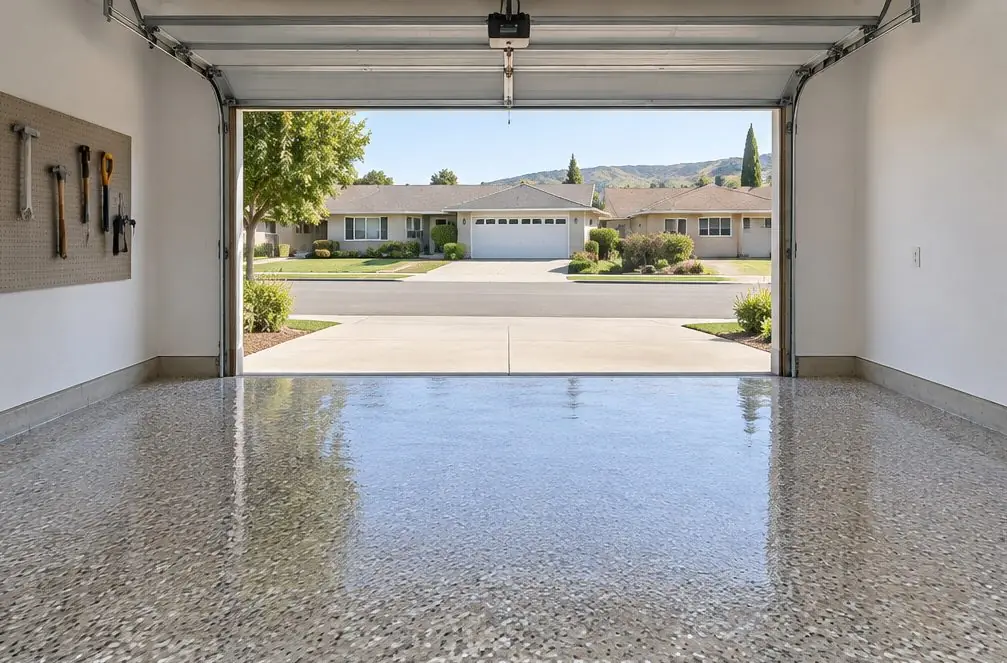 Illustration: a clean two-car Hayward garage with a freshly coated gray-and-tan flake epoxy floor, the door open to a driveway and a tract-home street