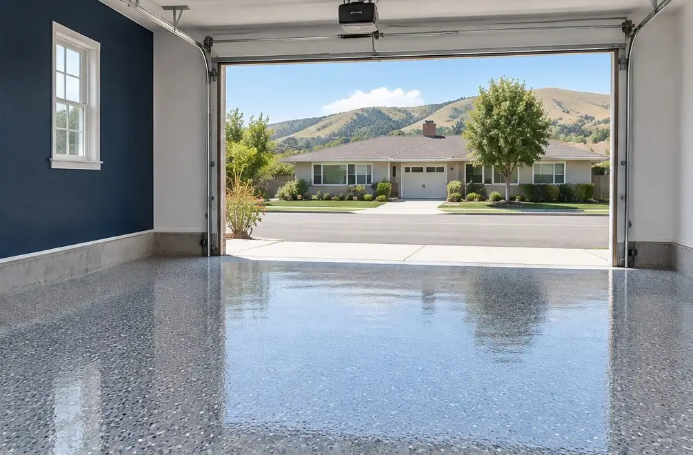 Illustration: a garage floor finished in a glossy gray flake coating with the door open to afternoon light